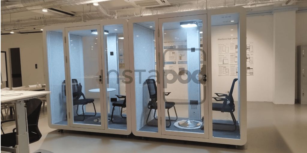 Interior space featuring soundproof booths with chairs and tables.