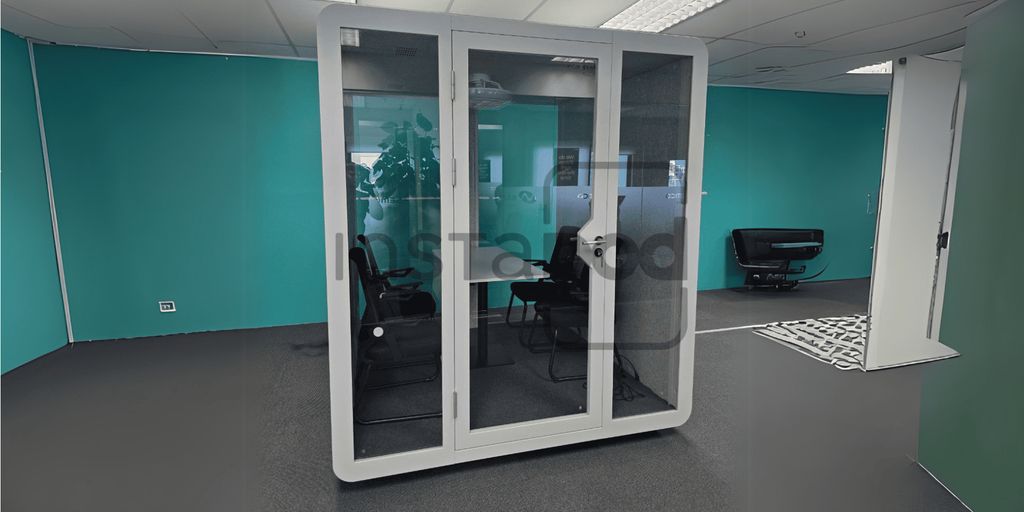 Modern office space featuring a glass meeting pod and furniture.