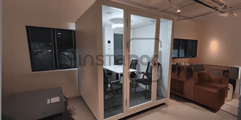 A modern, glass-walled meeting pod in an office setting.