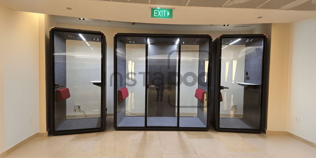 Glass pods in a modern office space with seating areas.