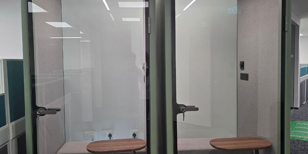 Two soundproof phone booths in a modern office space.