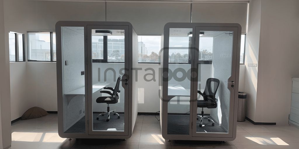 Two modern soundproof booths in a spacious office setting.