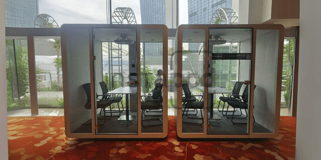 Two modern glass-walled meeting pods inside a bright office.