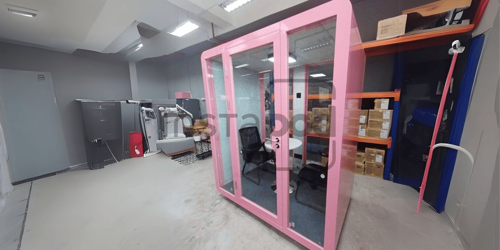 A pink soundproof booth with chairs in a modern office.