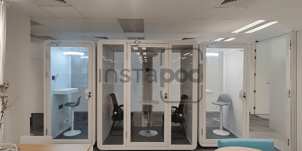 Modern office space with transparent soundproof pods for meetings.