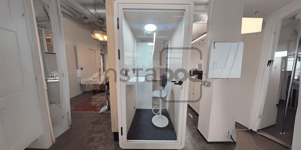 A modern soundproof booth with a minimalist design and chair.