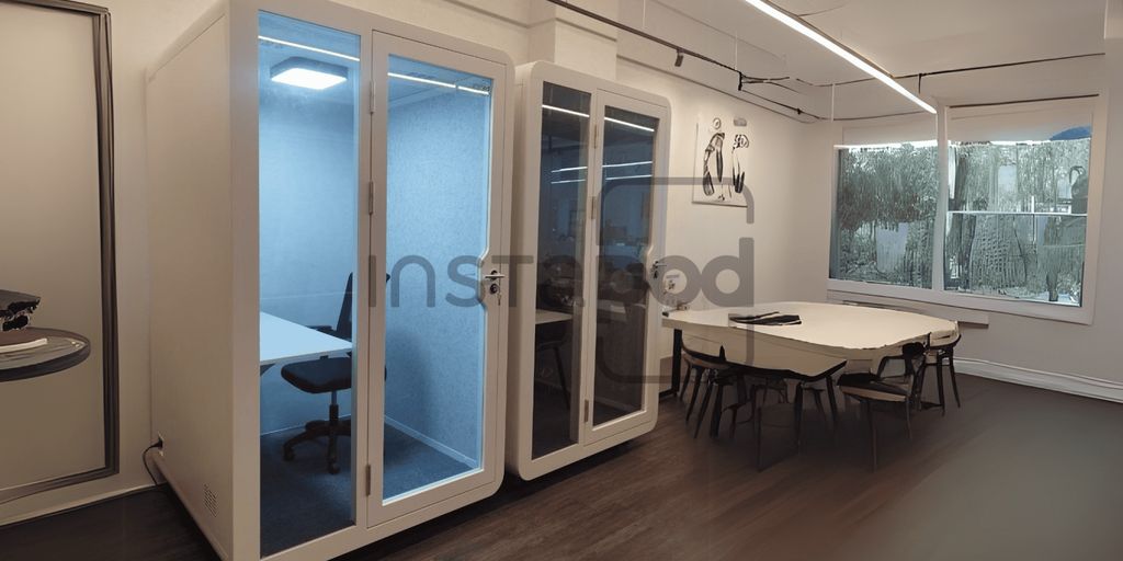 Modern office space featuring soundproof booths and meeting area.