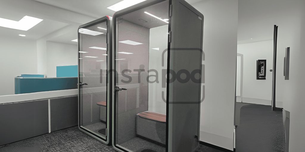 Two modern soundproof booths in a contemporary office setting.