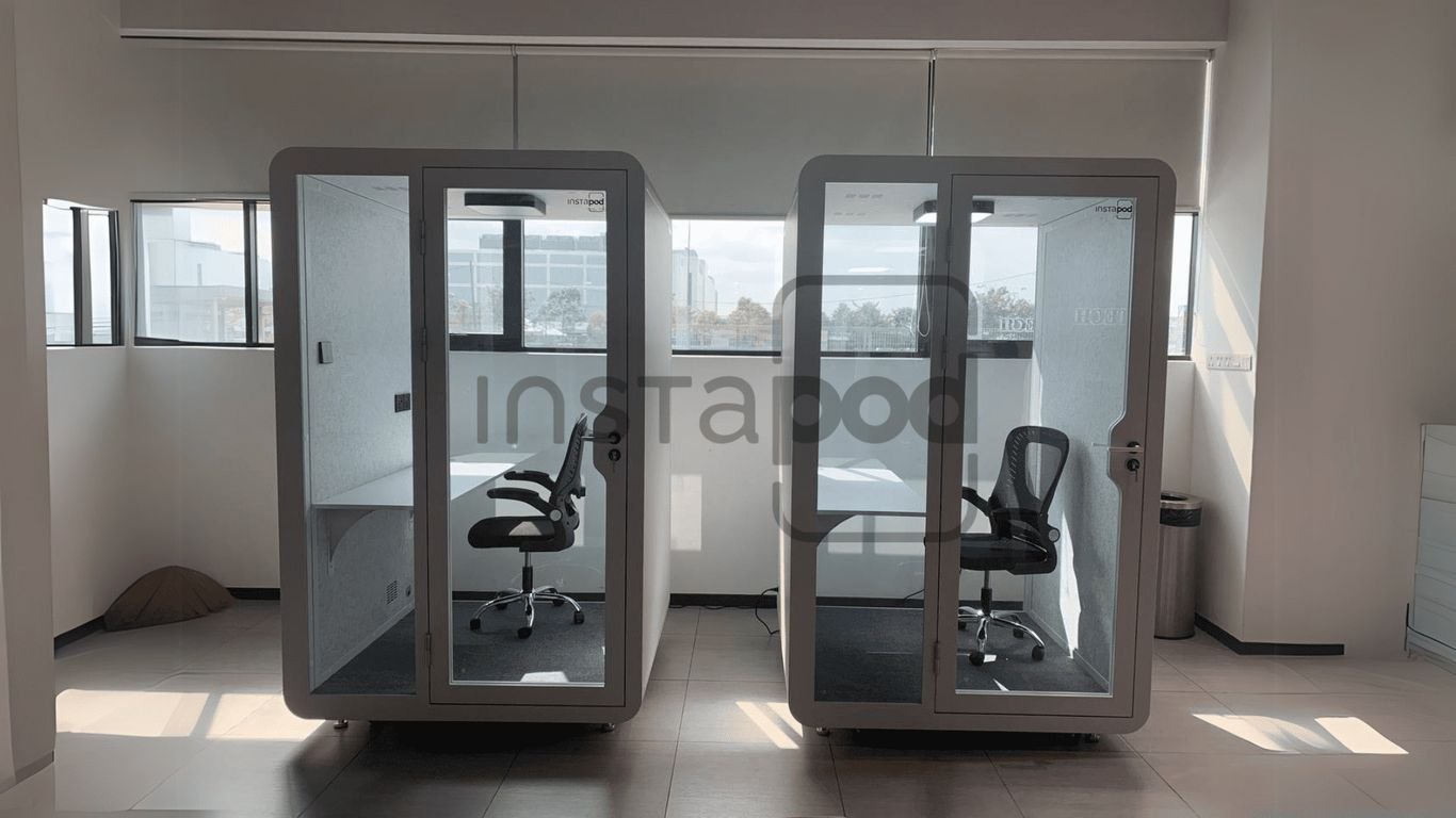 Two modern soundproof booths in a spacious office setting.