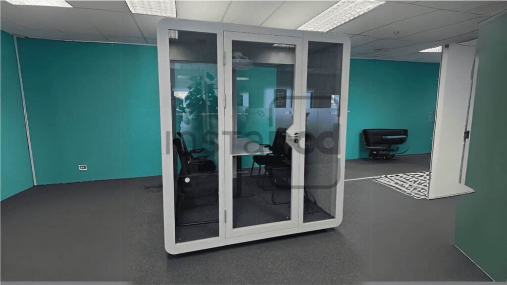 Modern office space featuring a glass meeting pod and furniture.