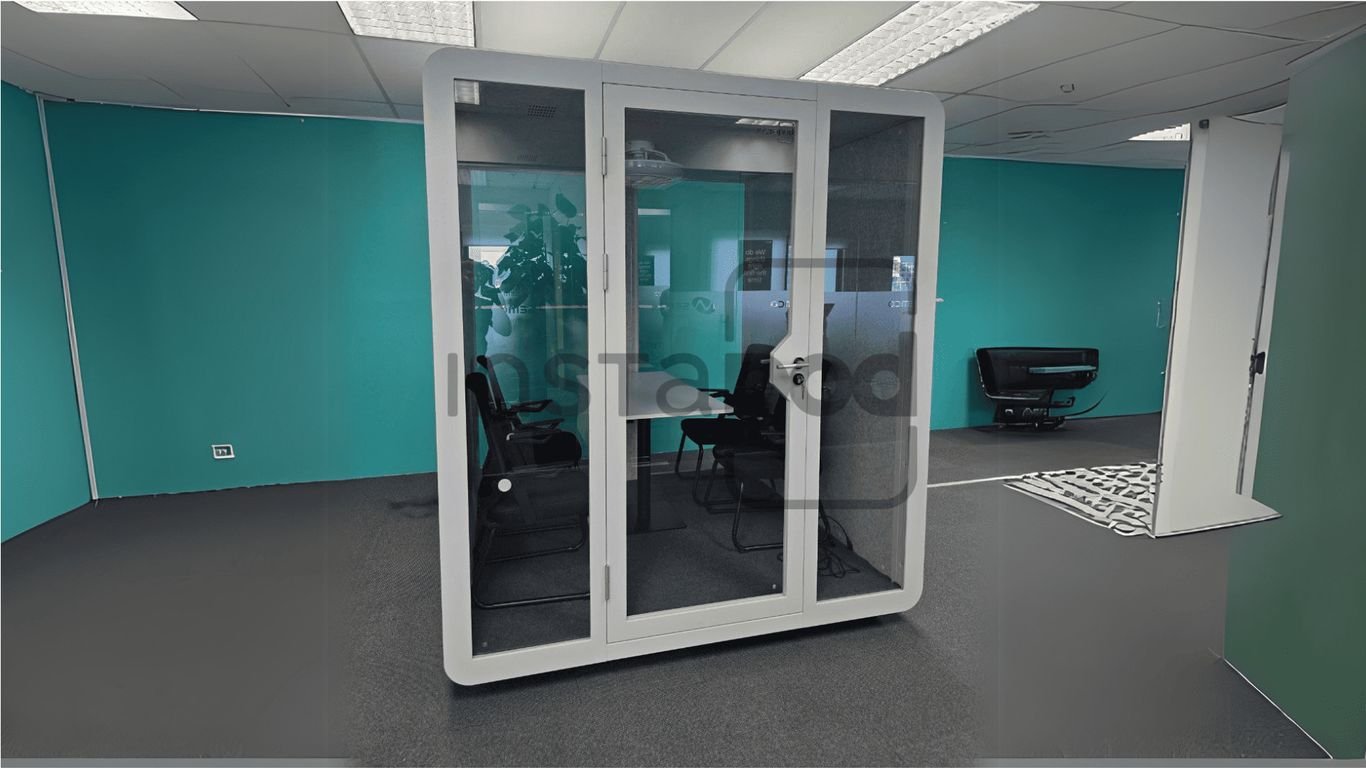 Modern office space featuring a glass meeting pod and furniture.