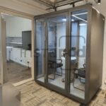 Modern office space featuring a glass meeting pod.