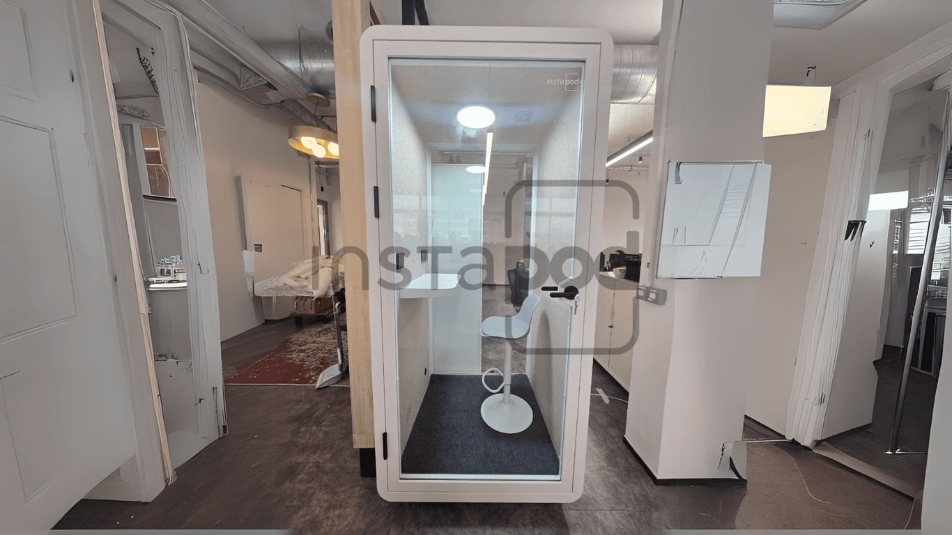 A modern soundproof booth with a minimalist design and chair.