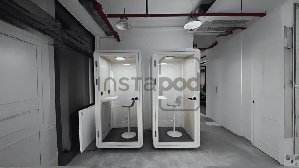 Two soundproof booths with chairs in a modern office space.