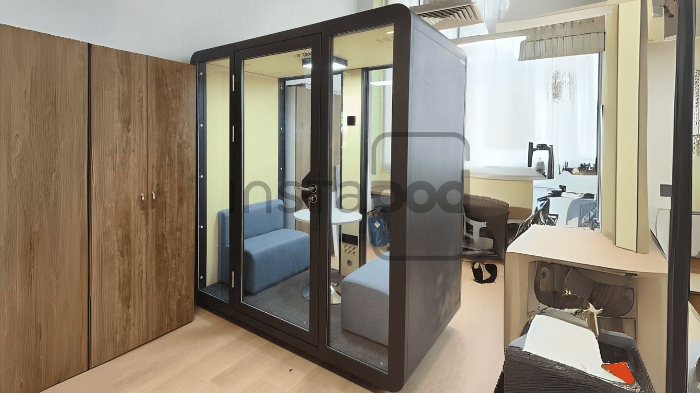 A compact meeting pod with seating and modern workspace elements.