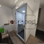 Modern office space featuring a glass-walled meeting pod.