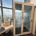 A modern office space featuring a soundproof booth and equipment.