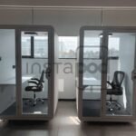 Two modern soundproof booths in a spacious office setting.