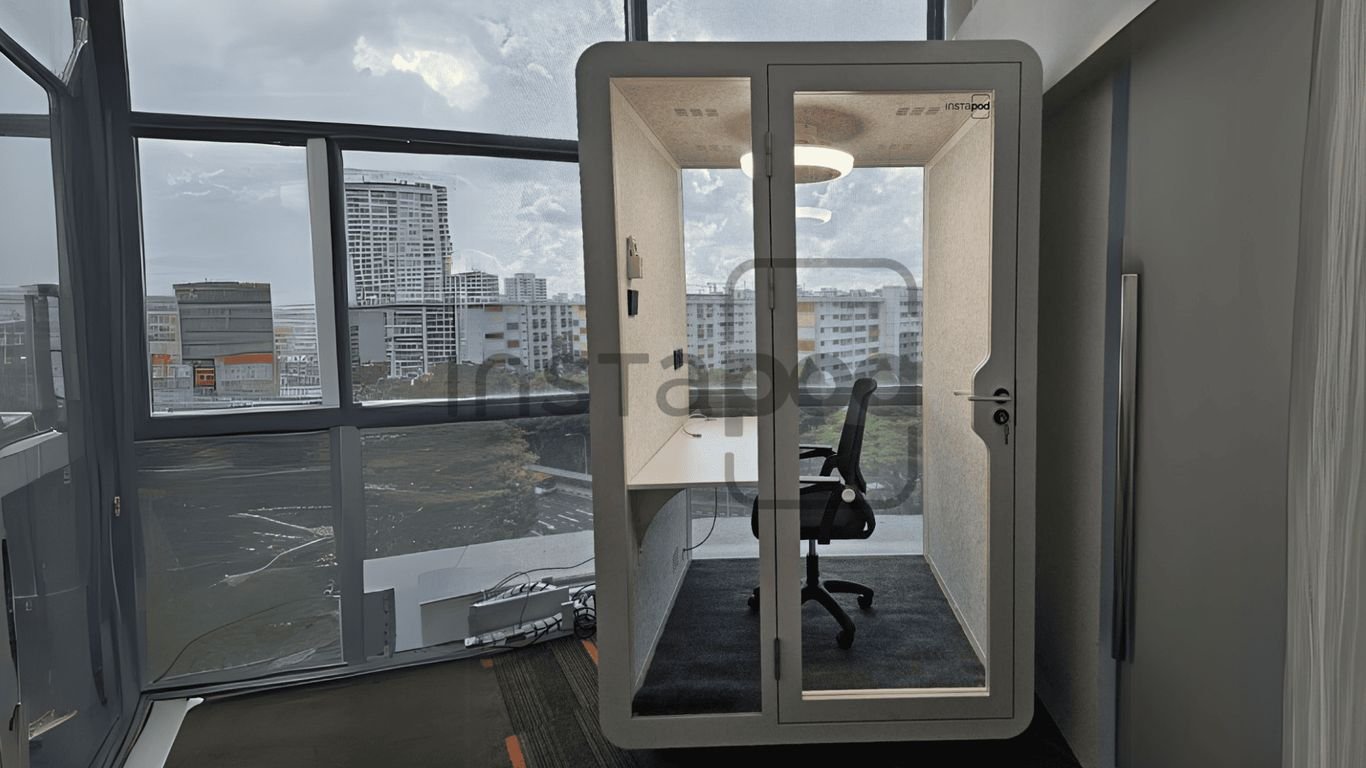 Modern office pod with glass walls and a desk inside.