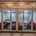 Modern workspace pod with seating and tables for collaboration.