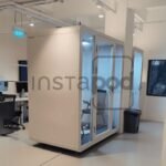 Modern office space featuring a glass-enclosed meeting pod.