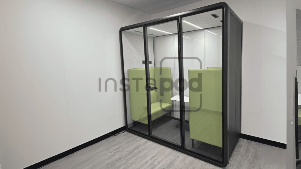 A modern glass pod with green seating for privacy and comfort.