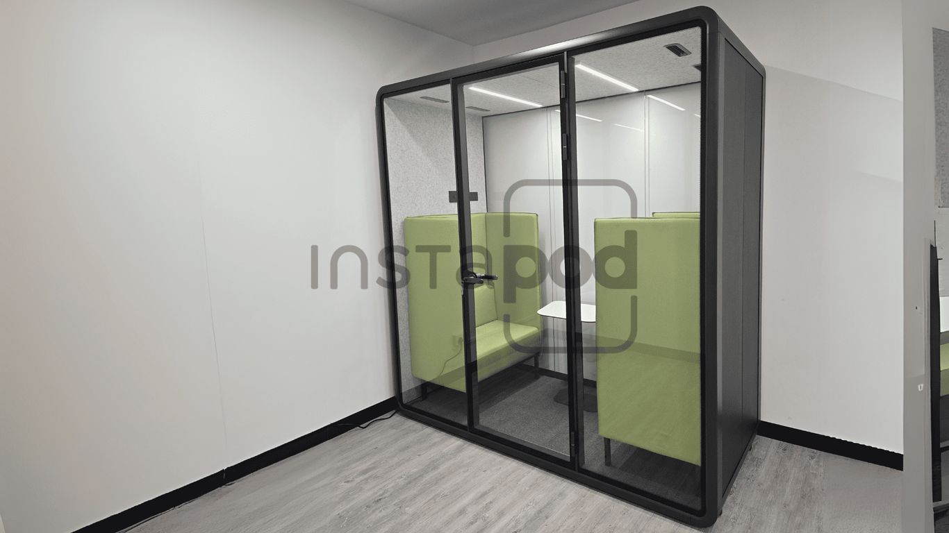 A modern glass pod with green seating for privacy and comfort.