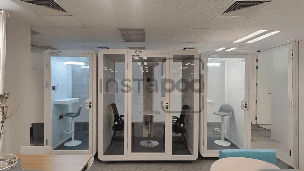Modern office space with transparent soundproof pods for meetings.