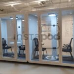Interior space featuring soundproof booths with chairs and tables.