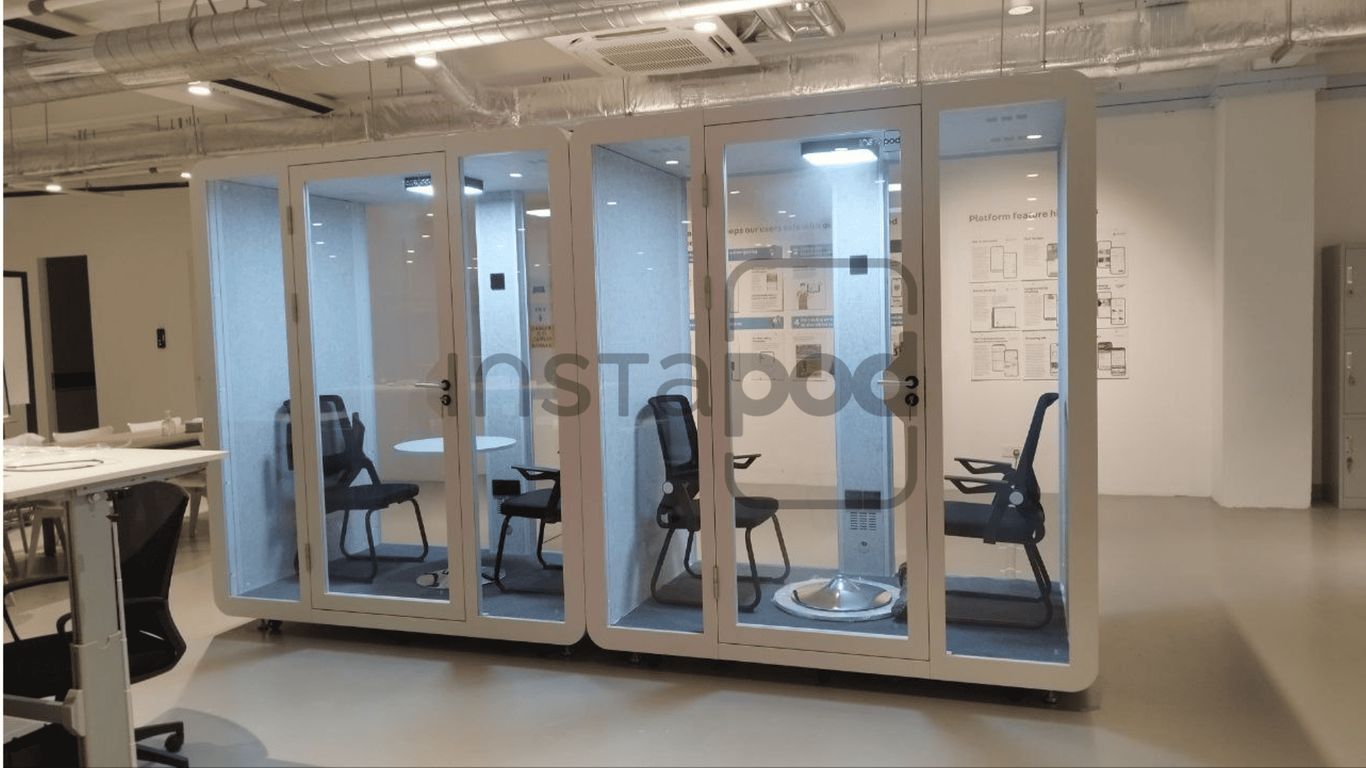 Interior space featuring soundproof booths with chairs and tables.