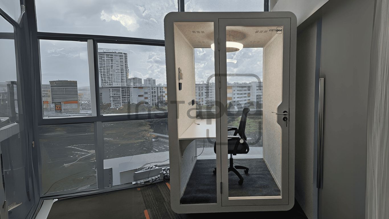 Modern office pod with glass walls and a desk inside.
