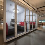 Modern office space featuring meeting pods and comfortable seating.