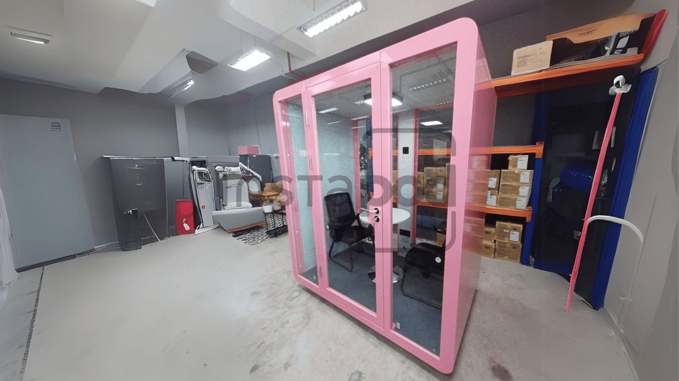 A pink soundproof booth with chairs in a modern office.