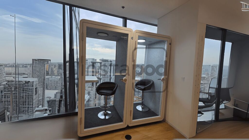 Two soundproof booths with chairs overlooking a city skyline.