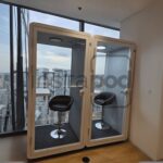 Two soundproof booths with chairs overlooking a city skyline.