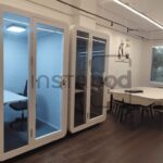 Modern office space featuring soundproof booths and meeting area.