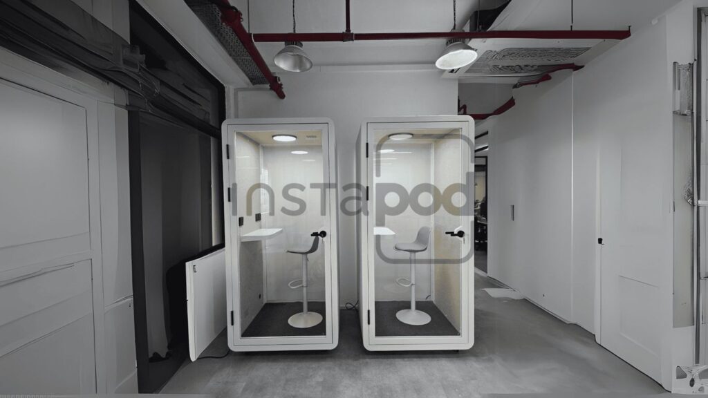 Two soundproof booths with chairs in a modern office space.