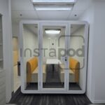A modern soundproof pod with seating in a minimalistic space.