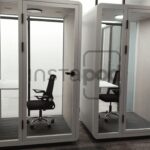 Two glass-walled office pods with chairs and desks inside.