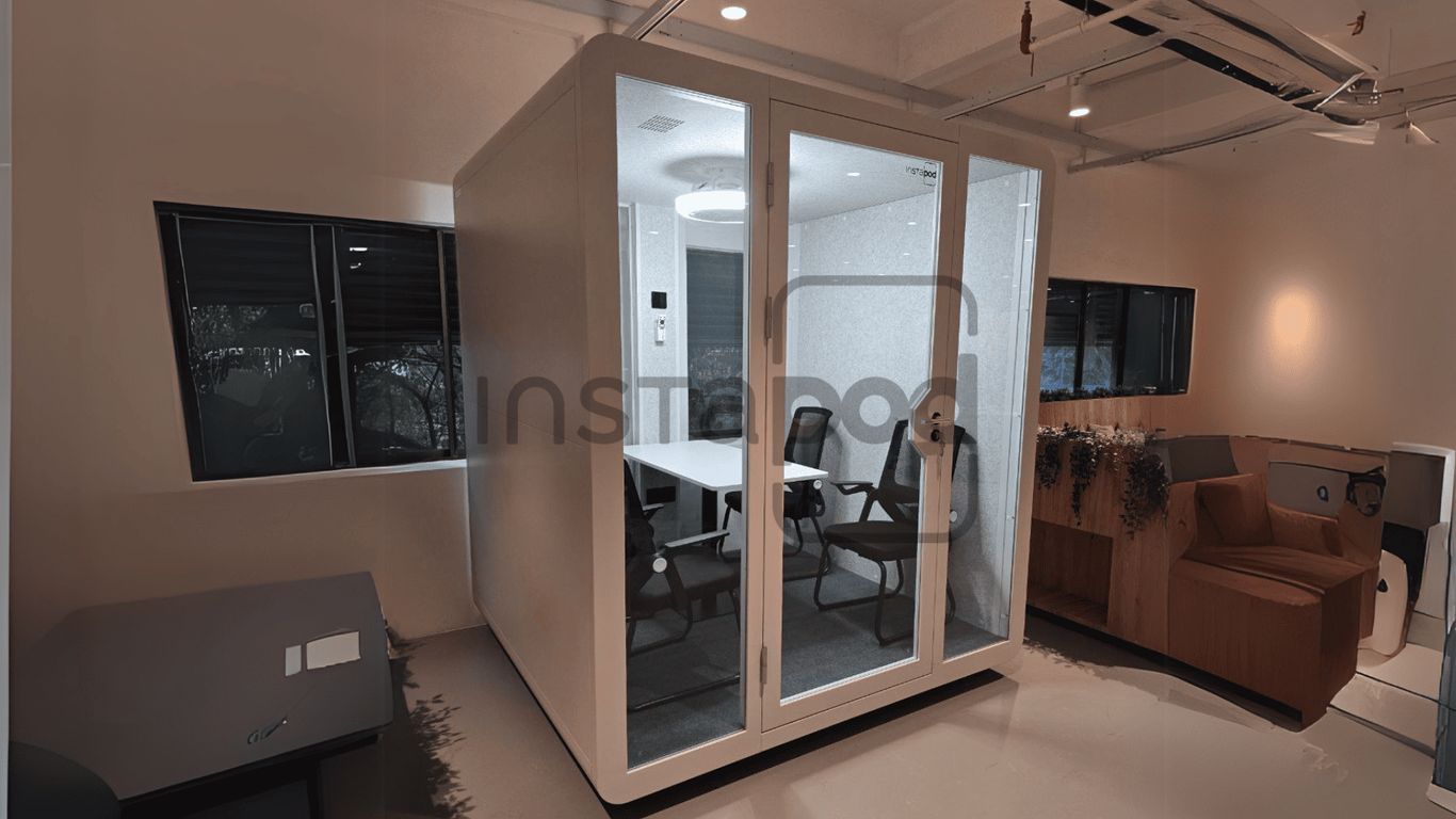 A modern, glass-walled meeting pod in an office setting.