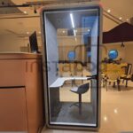 Modern workspace with a soundproof booth and seating area.