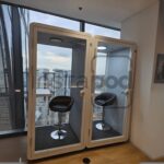 Two soundproof pods with chairs in a modern office space.