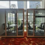 Two modern glass-walled meeting pods inside a bright office.