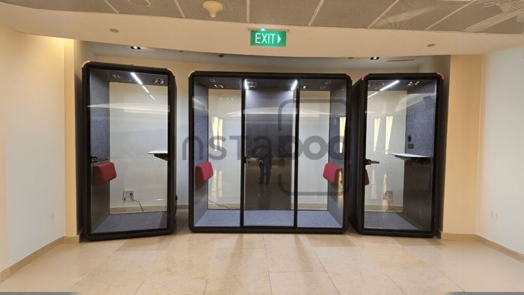 Glass pods in a modern office space with seating areas.