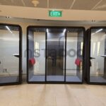 Glass pods in a modern office space with seating areas.