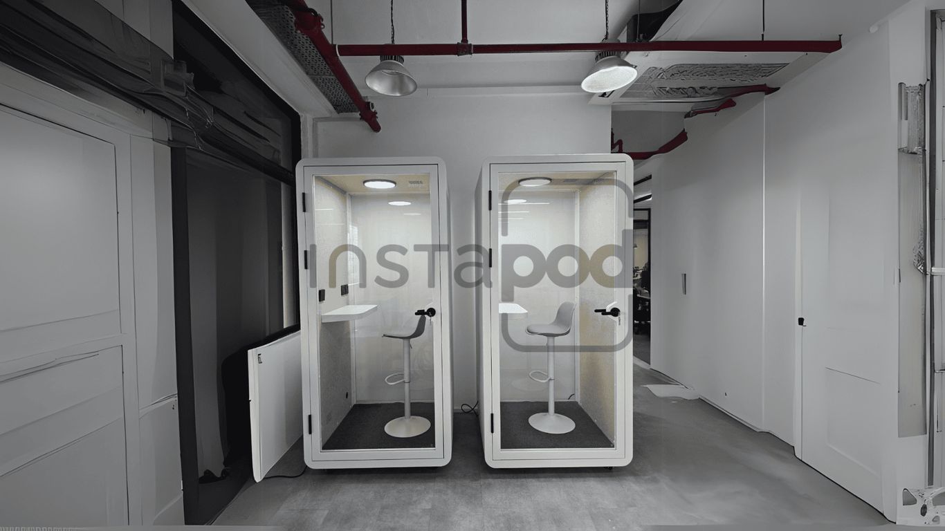 Two soundproof booths with chairs in a modern office space.