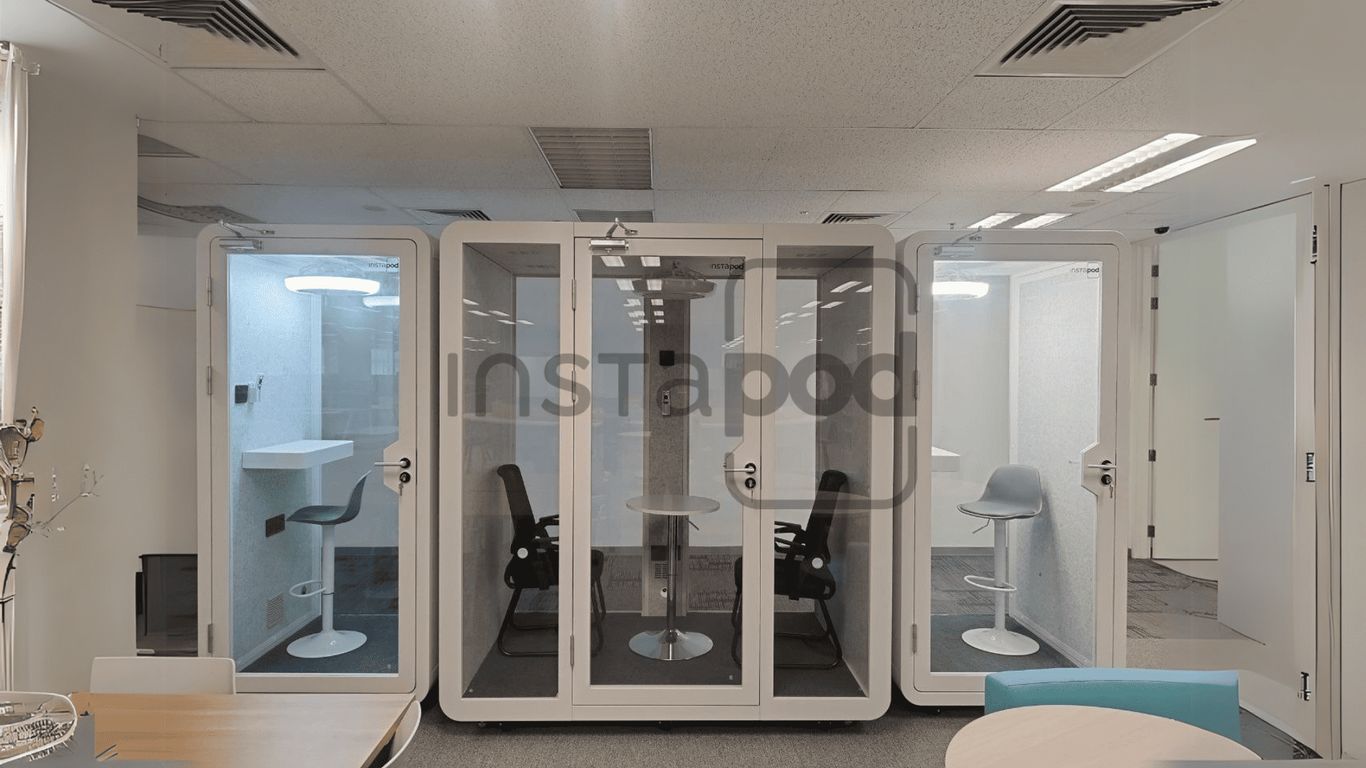 Modern office space with transparent soundproof pods for meetings.