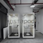 Two soundproof booths with chairs in a modern office space.