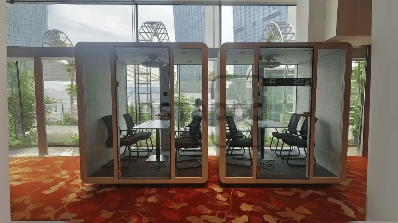 Two modern glass-walled meeting pods inside a bright office.